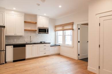 A kitchen with white cabinets and a black countertop.