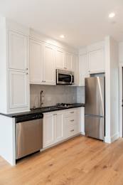 A kitchen with white cabinets and a black countertop.