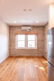 A room with wooden floors and a window with a curtain.