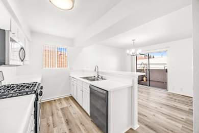 A modern kitchen with white appliances and wooden floors.
