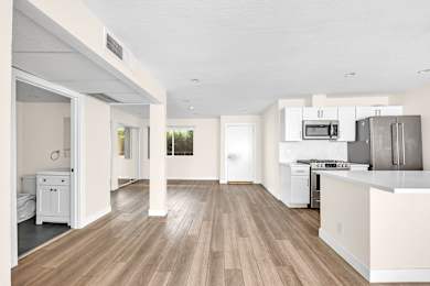 A kitchen with white cabinets and a wooden floor.