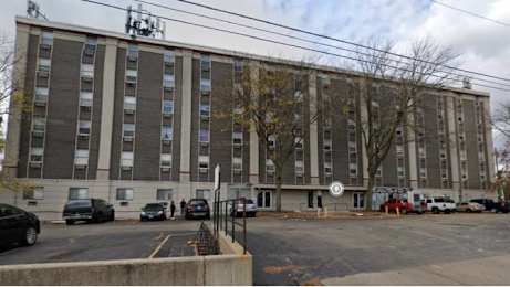 A large grey building with a parking lot in front.