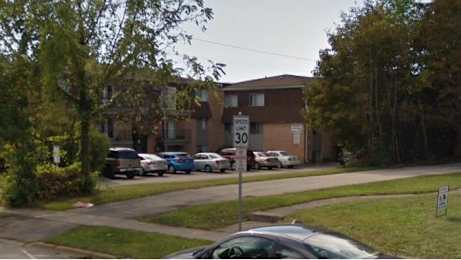 A street view of a residential area with cars parked on the side of the road.