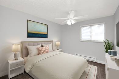 A bedroom with a large bed, a ceiling fan, and a painting on the wall.