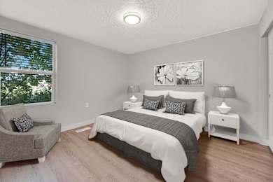 A bedroom with a bed, nightstand, and chair.