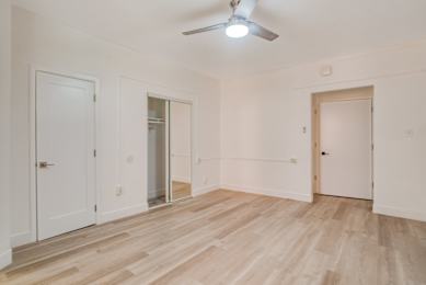 A room with wooden floors and white walls, with a ceiling fan and three doors at Clay & Tiffany, Portland, 97201