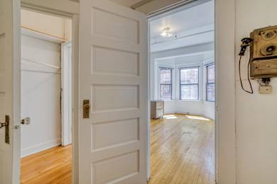 A white door with a brass handle is open to a room with wooden floors and a window at Clay & Tiffany, Portland, 97201