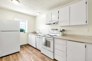 A white kitchen with wood floors and white appliances.
