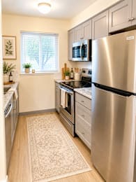 Galley kitchen with stainless refrigerator and microwave at Laurel on 2nd Apartments, Oregon