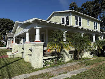 A white house with a green roof and a porch.