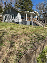 A house with a grey roof and white walls is situated on a steep hill.