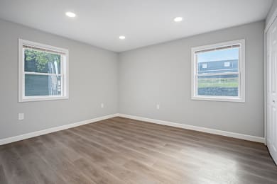 A room with light grey walls and a wooden floor at Palisades Apartments in Kansas City, MO 64133