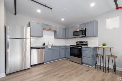 A kitchen with a refrigerator, microwave, oven, and sink.
