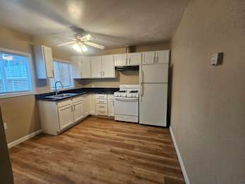 A kitchen with white appliances and wooden floors.