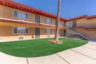 the courtyard of a building with a palm tree and green grass