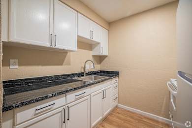A kitchen with white cabinets and a black countertop.