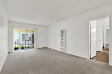 an empty living room with a door to a balcony at Olive Tree Apartments, California