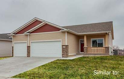 a beige house with a front porch and a garage at Two Rivers Home Rentals, Iowa 50266