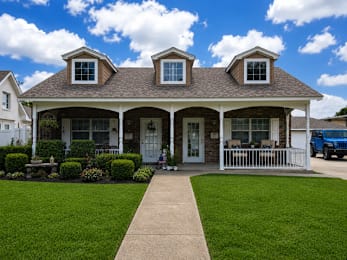 A house with a white picket fence and a blue car parked in front.