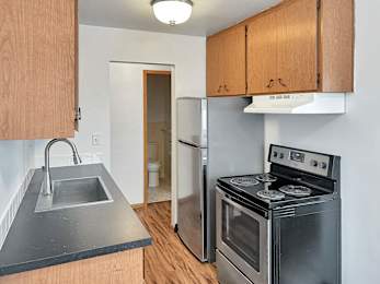 A kitchen with a stove, sink, and cabinets.