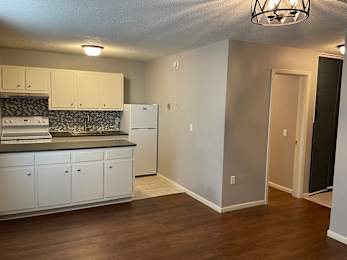 A kitchen with white cabinets and a black and white backsplash.