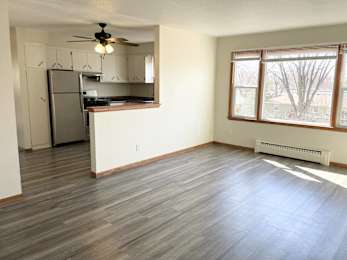 A kitchen with a refrigerator, cabinets, and a ceiling fan.