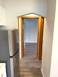 A kitchen with a refrigerator and a doorway leading to another room.
