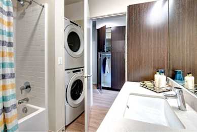 A modern bathroom with full size washer and dryer.