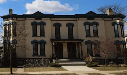 A large, two-story house with a dark roof and a front porch.