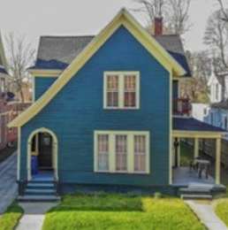 A blue house with a yellow roof and a porch.