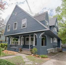 A blue house with a porch and a front yard.