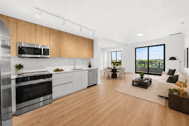 A modern kitchen with wooden floors and stainless steel appliances.