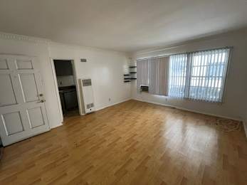 A room with wooden flooring and a window with blinds.