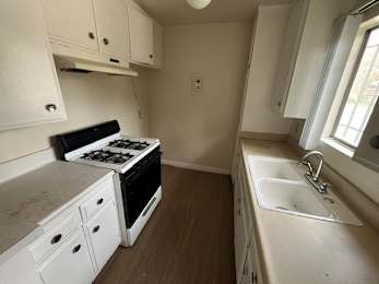A small kitchen with a stove, sink, and cabinets.