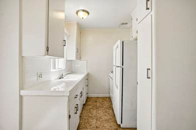 A white kitchen with a sink and a refrigerator.