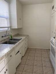 A kitchen with white cabinets and a tiled floor.