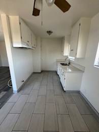 A kitchen with white cabinets and a fan.