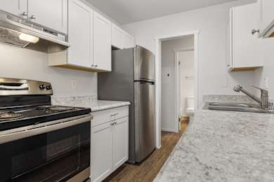 A kitchen with white cabinets and a stainless steel refrigerator.