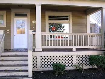 A house numbered 432 with a white door and a window with a red curtain.