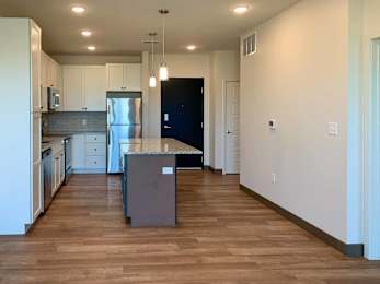 a kitchen with white cabinets, granite counter tops, and hardwood floors