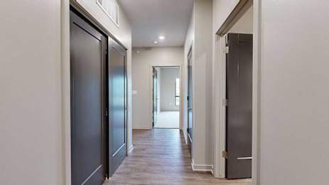 A hallway with a closet to the side, and an open door to a bedroom at the end.