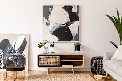A living room with a large painting on the wall and a chair in front of it.
