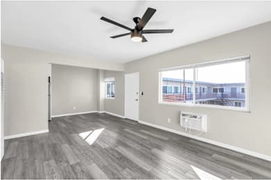 A spacious room with a ceiling fan and a large window.