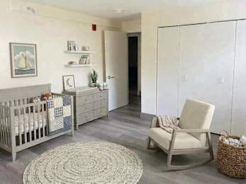 A baby's room with a crib, chair, and a rug.