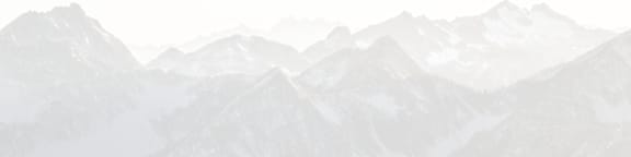 A mountain range covered in snow under a hazy sky.