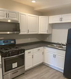 A kitchen with white cabinets and a black refrigerator.
