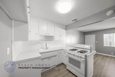 A modern kitchen with a stove top oven and white cabinets.
