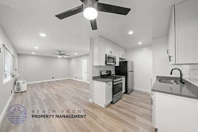A spacious kitchen and living room with a fan and a refrigerator.