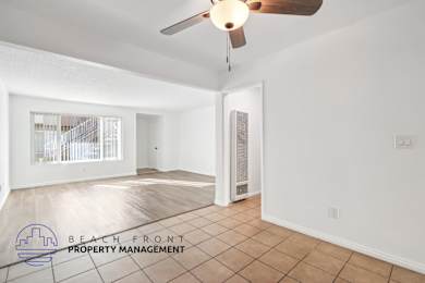 A spacious room with a ceiling fan and a logo for Beach Front Property Management.