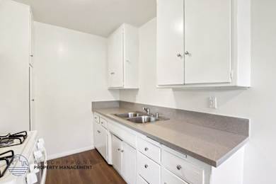 A kitchen with white cabinets and a stove top oven.